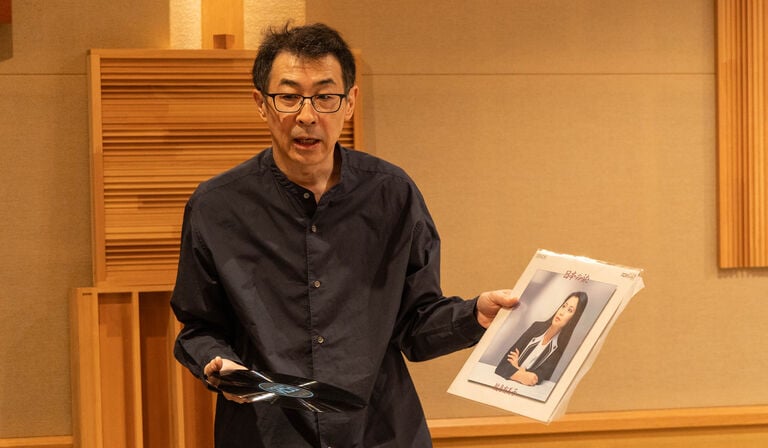 A man speaking while holding an album