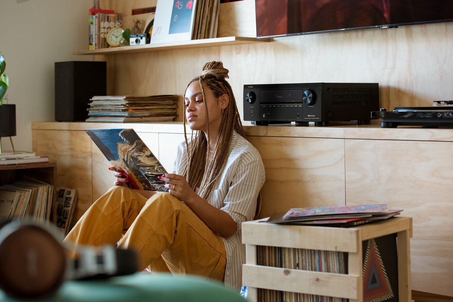 A woman looking at an album, sitting by an AVR and turntable