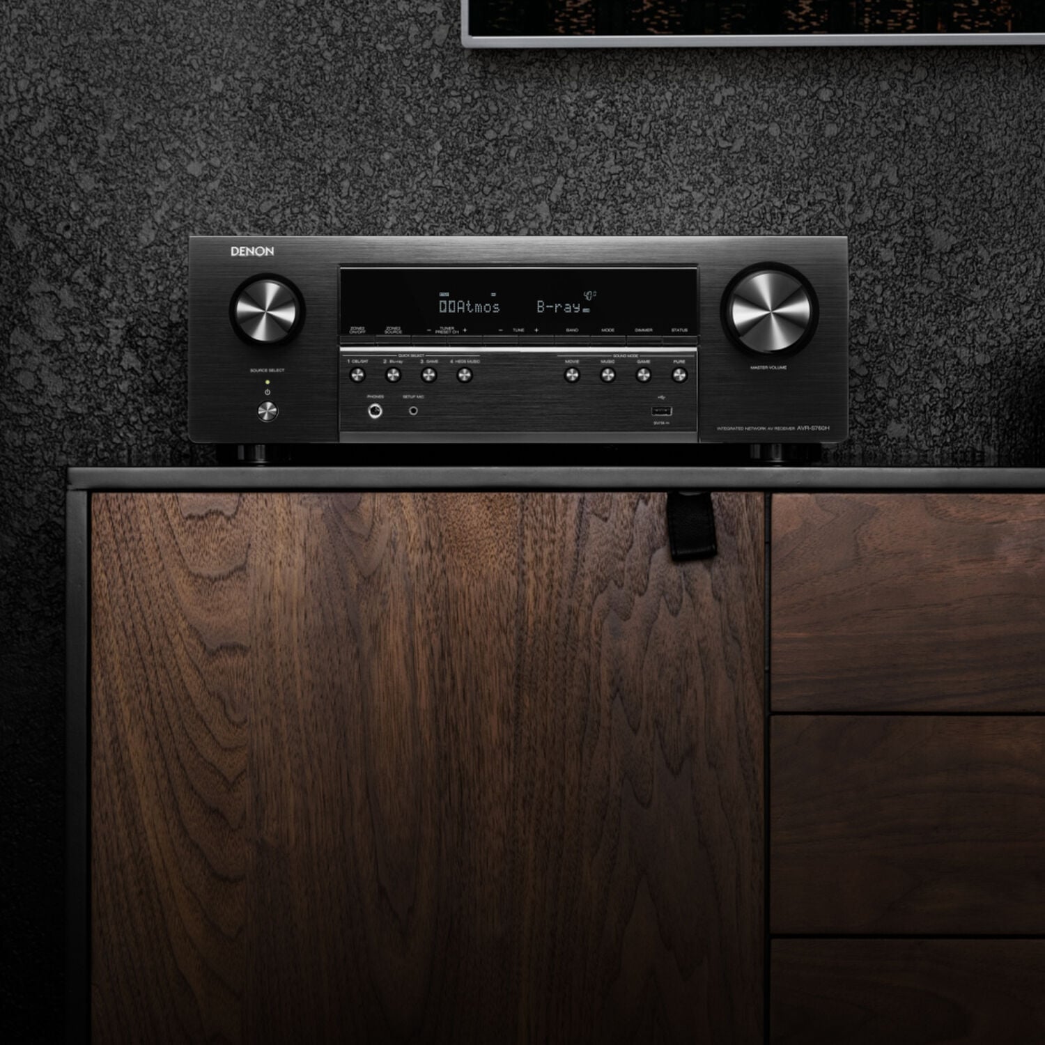 AVR-S760H sitting on a tv-stand next to a floor-standing speaker