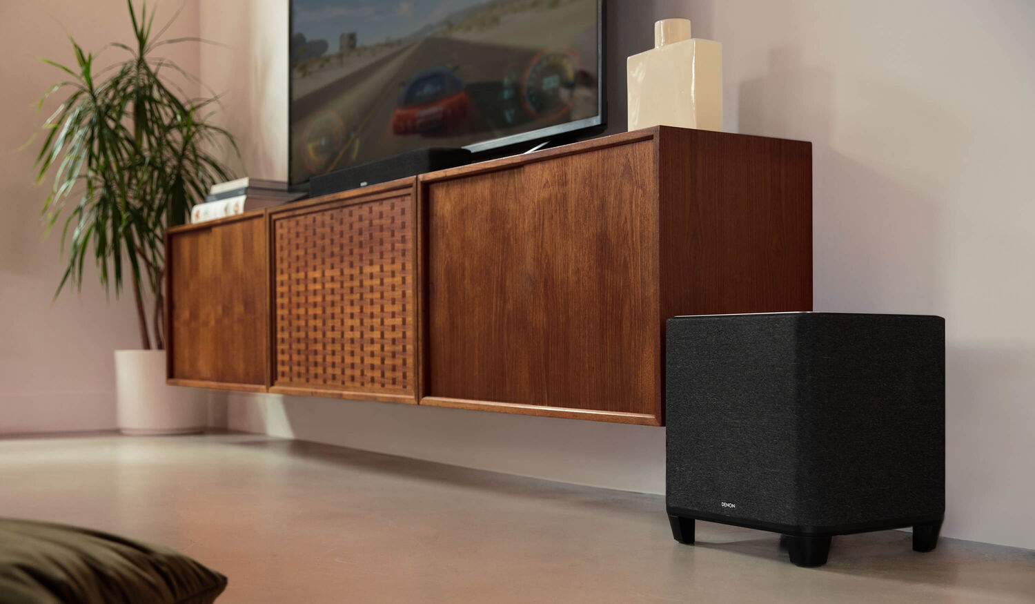 Denon Home subwoofer on the floor near a tv