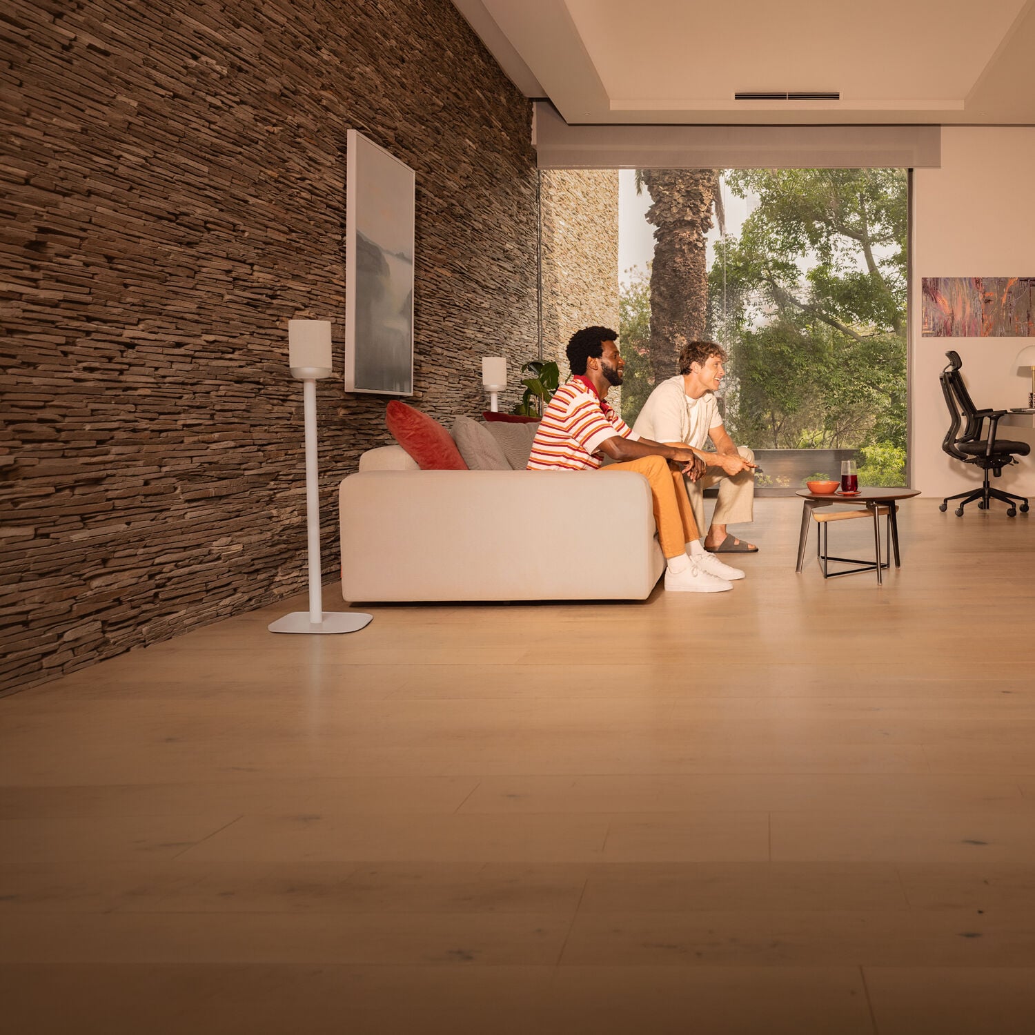 Two men watching a TV surrounded by a wireless home theater